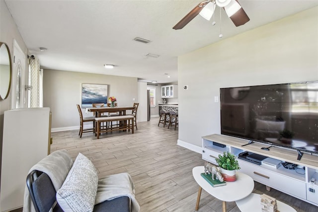 living room with visible vents, baseboards, ceiling fan, and wood tiled floor