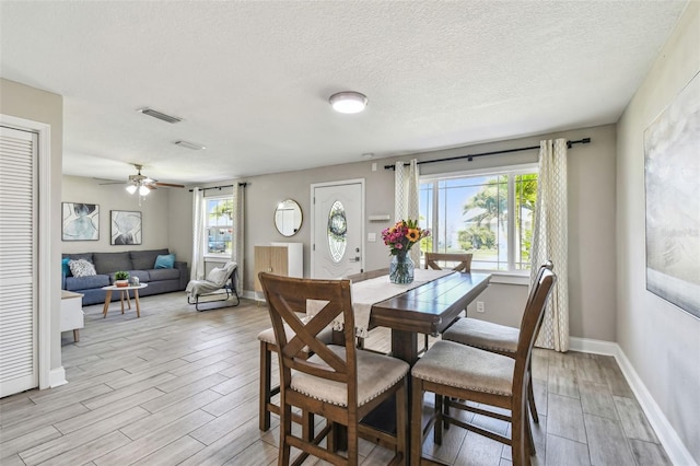 dining room with visible vents, a textured ceiling, baseboards, ceiling fan, and wood tiled floor