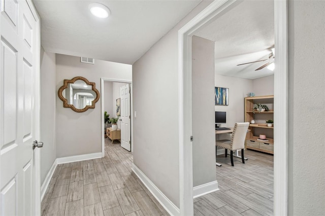 hallway with visible vents, baseboards, and wood tiled floor