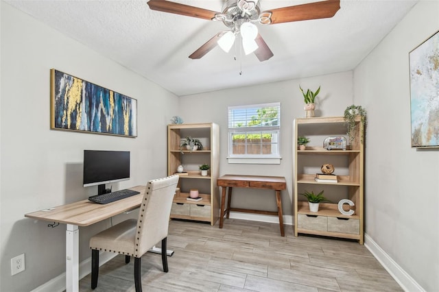 office space with a textured ceiling, light wood-style flooring, baseboards, and ceiling fan