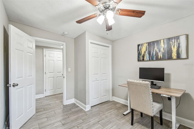 office with light wood-style flooring, a textured ceiling, baseboards, and a ceiling fan