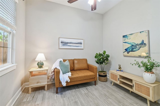 living area featuring a ceiling fan, wood finished floors, and baseboards