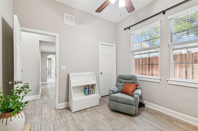 living area with visible vents, baseboards, ceiling fan, and light wood finished floors