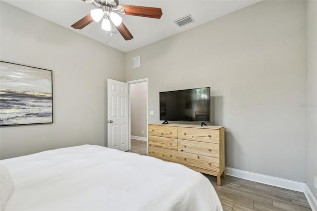 bedroom featuring visible vents, a ceiling fan, baseboards, and wood finished floors