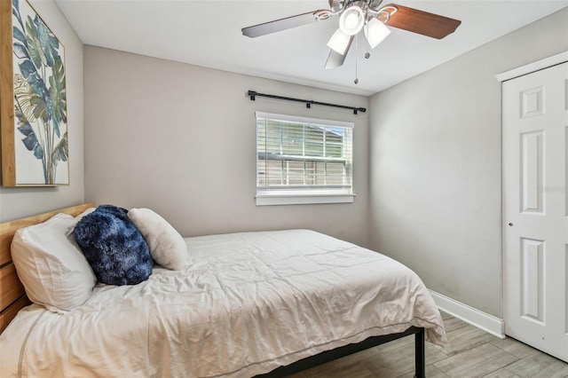 bedroom featuring ceiling fan, baseboards, and wood finished floors