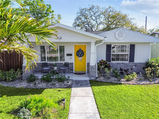 view of front of property with a front lawn, fence, stone siding, and stucco siding