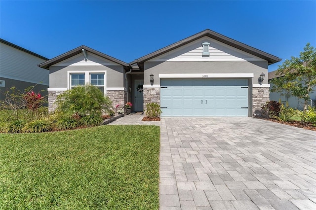 view of front of property featuring decorative driveway, stone siding, a garage, and stucco siding