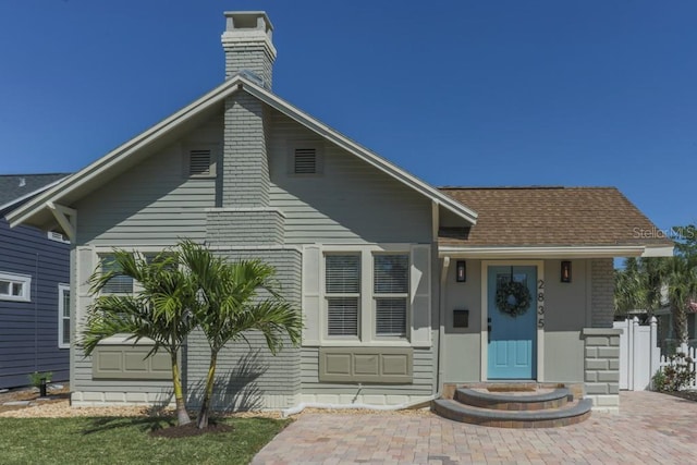 view of front of home featuring a chimney and a shingled roof