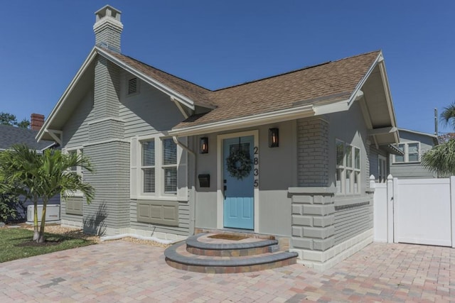 view of front of home with fence, roof with shingles, and a gate