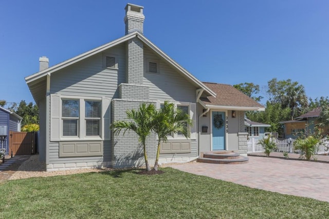 bungalow-style home featuring a chimney, a front lawn, and fence