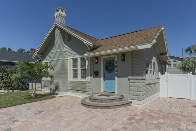 view of front of property featuring a gate, fence, and a chimney