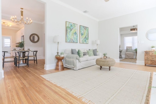 living area featuring light wood-type flooring, an inviting chandelier, and ornamental molding