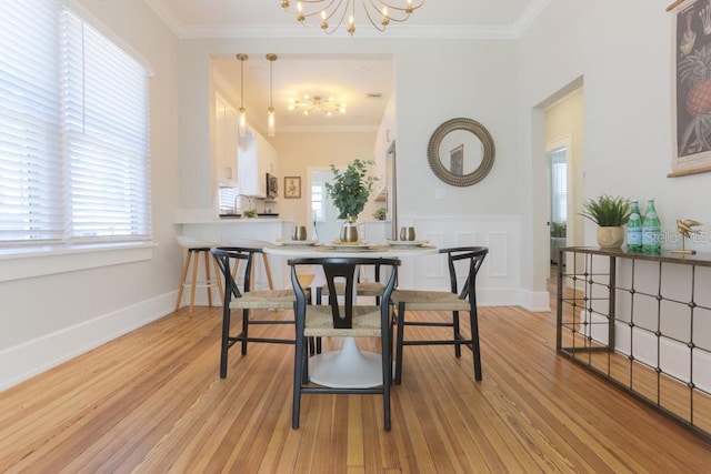 dining space with a chandelier, baseboards, crown molding, and light wood-style floors