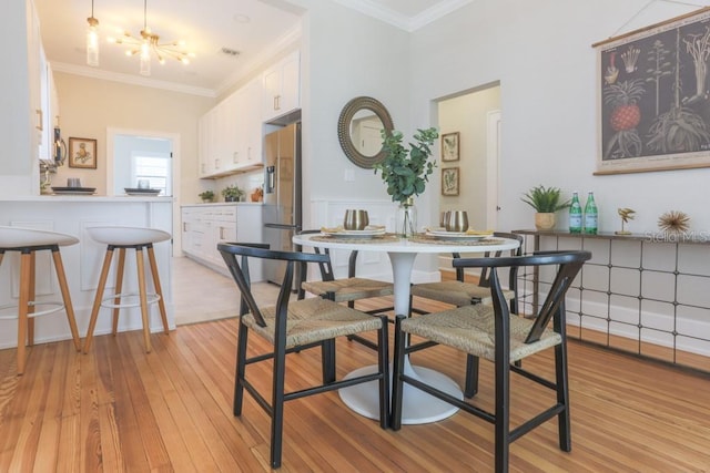 dining room featuring visible vents, light wood-style floors, and ornamental molding