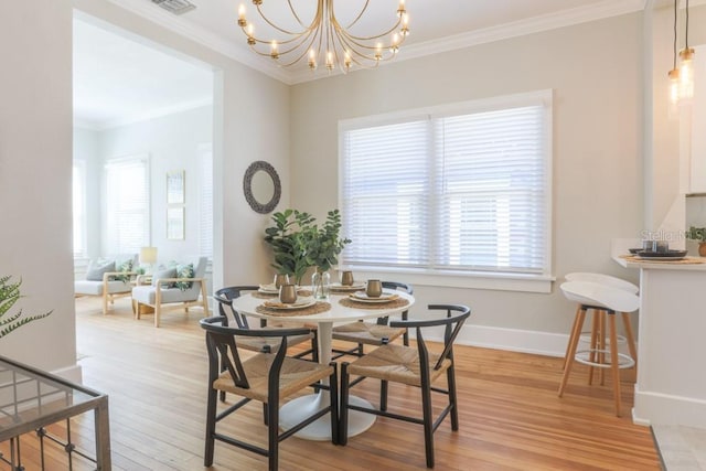 dining space featuring an inviting chandelier, crown molding, light wood-style floors, and baseboards