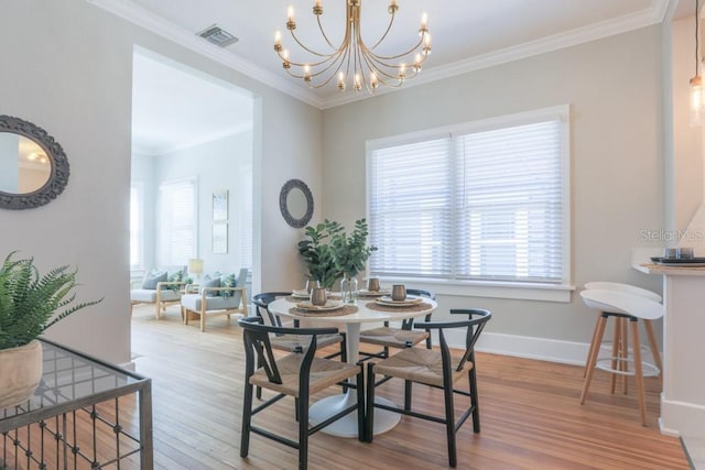 dining area featuring light wood finished floors, visible vents, baseboards, a chandelier, and ornamental molding