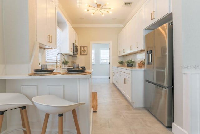 kitchen with visible vents, a peninsula, stainless steel appliances, light countertops, and a notable chandelier