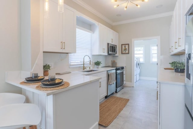 kitchen with a sink, stainless steel appliances, white cabinets, crown molding, and light countertops