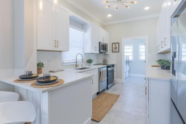 kitchen with a breakfast bar, ornamental molding, stainless steel appliances, white cabinetry, and a sink