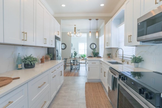 kitchen with a chandelier, stainless steel appliances, crown molding, and a sink