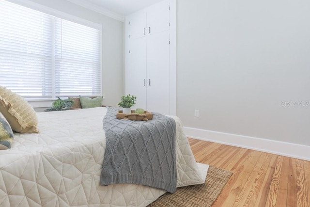 bedroom featuring crown molding, baseboards, and light wood finished floors