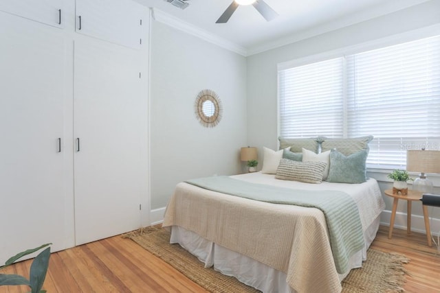 bedroom featuring visible vents, wood finished floors, ornamental molding, and a ceiling fan