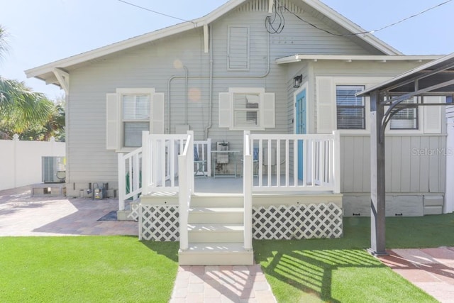 rear view of property featuring a patio area, a yard, and fence