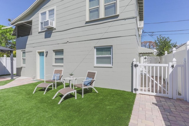 rear view of house with cooling unit, fence, and a yard