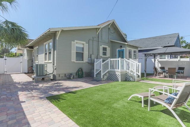 back of house featuring a gate, fence, a gazebo, a patio area, and a lawn