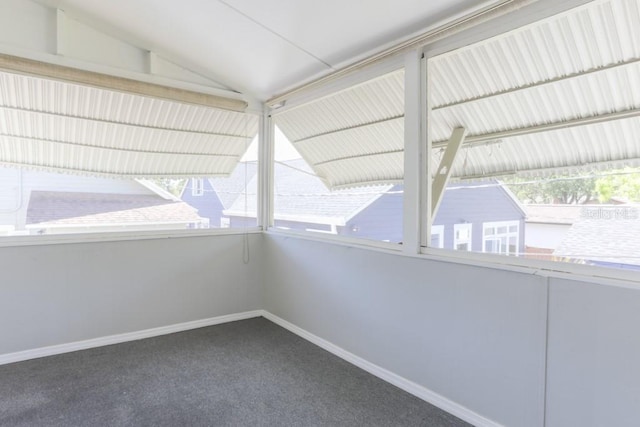 carpeted empty room featuring baseboards and lofted ceiling