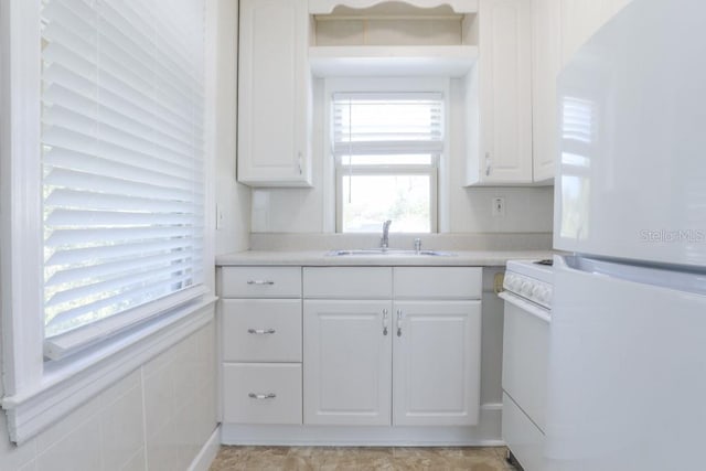 kitchen with white appliances, white cabinets, light countertops, and a sink