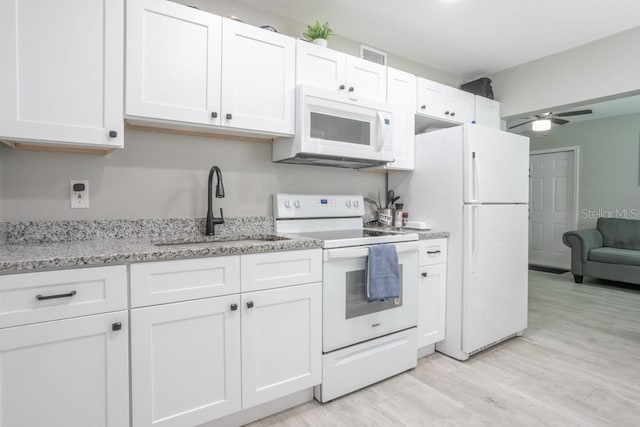 kitchen featuring light wood-type flooring, a sink, white appliances, white cabinets, and ceiling fan