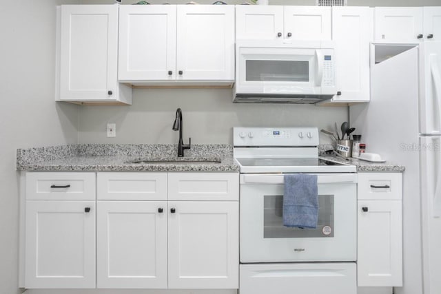 kitchen featuring light stone counters, white cabinets, white appliances, and a sink