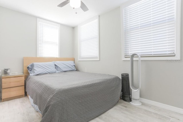 bedroom with light wood-type flooring, baseboards, and ceiling fan