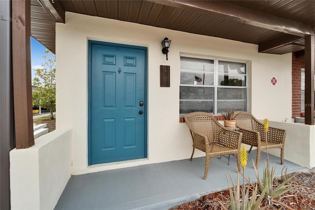 property entrance featuring stucco siding and a porch