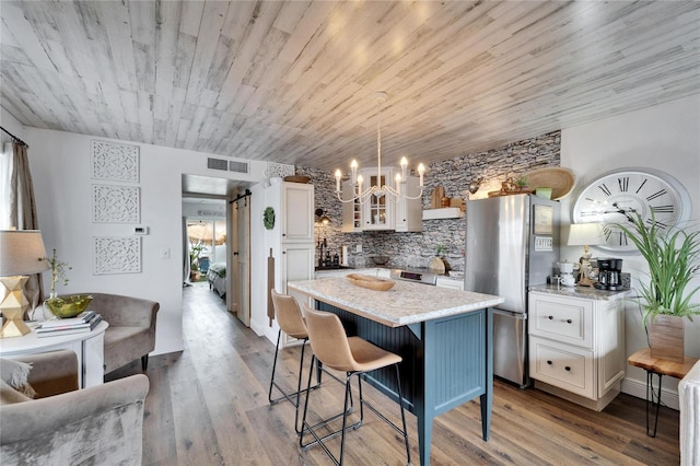 kitchen featuring white cabinets, glass insert cabinets, visible vents, and freestanding refrigerator