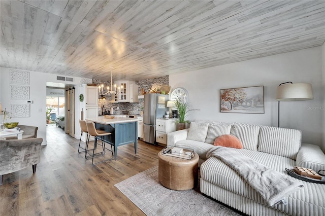 living area featuring wooden ceiling, a notable chandelier, wood finished floors, and visible vents