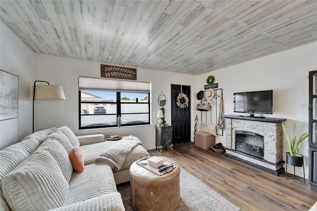 living area featuring a stone fireplace, wood ceiling, and wood finished floors