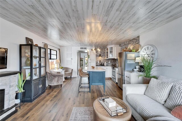 living area with dark wood-style floors, visible vents, a fireplace, and an inviting chandelier