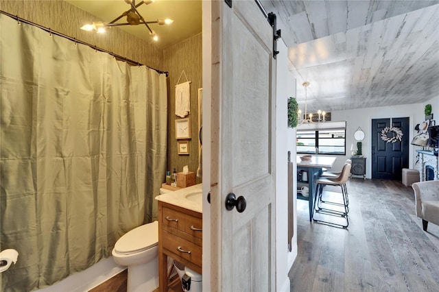 full bathroom with wood finished floors, toilet, a chandelier, and vanity