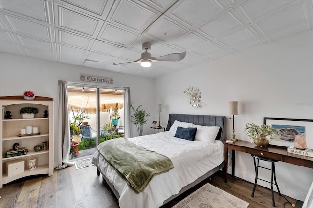 bedroom featuring a ceiling fan, access to outside, an ornate ceiling, wood finished floors, and baseboards