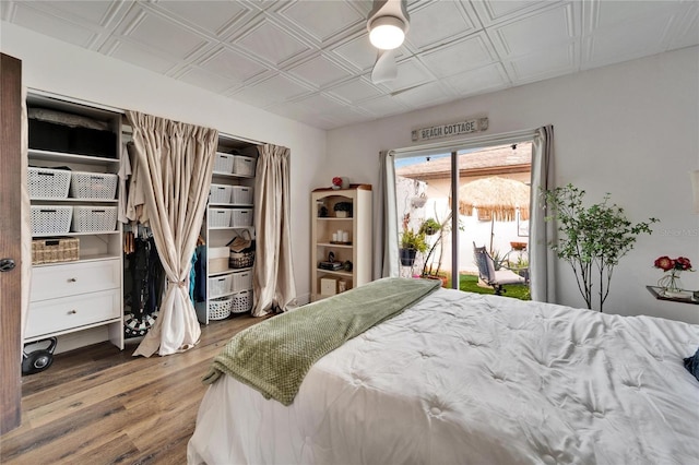 bedroom with access to outside, wood finished floors, and an ornate ceiling