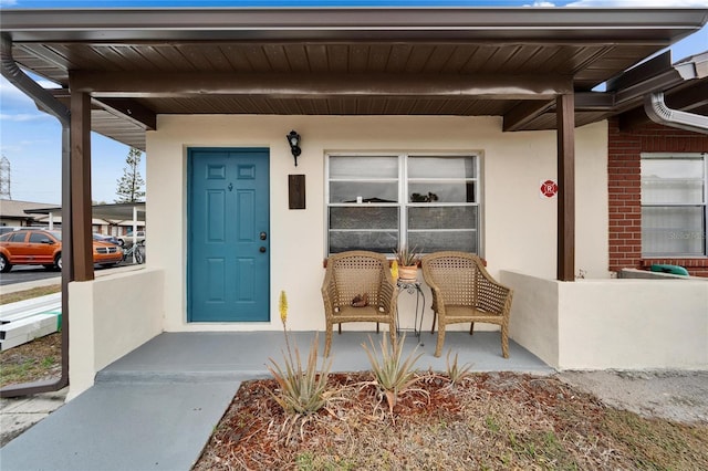 view of exterior entry featuring covered porch and stucco siding