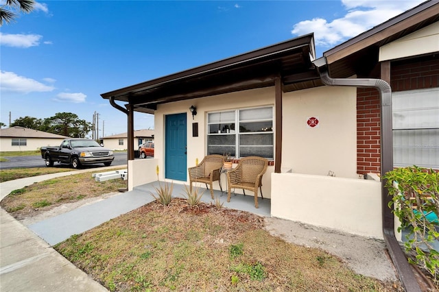 view of front of property with stucco siding, brick siding, and covered porch