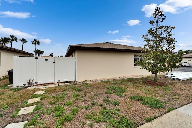 view of property exterior featuring a gate, fence, and stucco siding