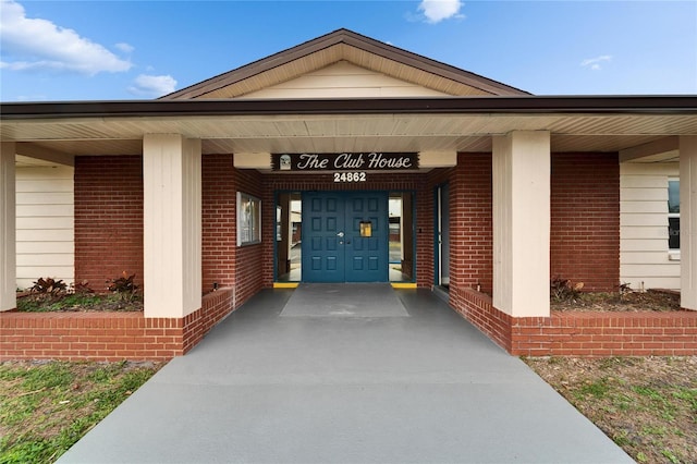 view of exterior entry featuring brick siding and covered porch