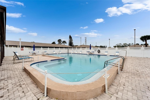 community pool with a patio and fence