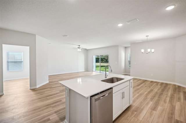 kitchen with light wood finished floors, a sink, open floor plan, and stainless steel dishwasher