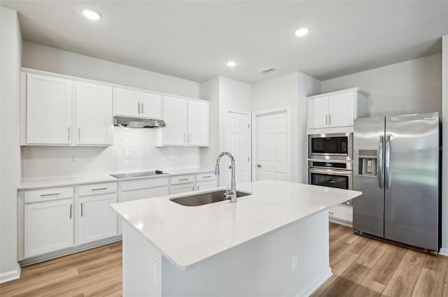 kitchen featuring under cabinet range hood, appliances with stainless steel finishes, light wood-type flooring, and a sink