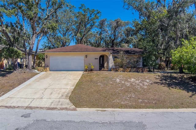 single story home with concrete driveway, an attached garage, and stucco siding